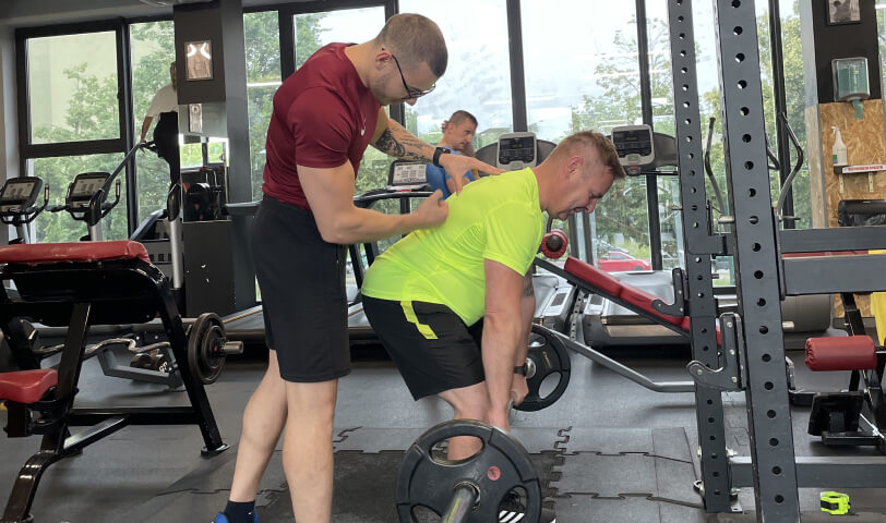 Trener personalny Robert Szałas nadzoruje technikę swojego podopiecznego podczas wykonywania rumuńskiego martwego ciągu ze sztangą.